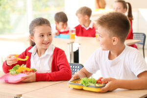 Happy school children eating lunch