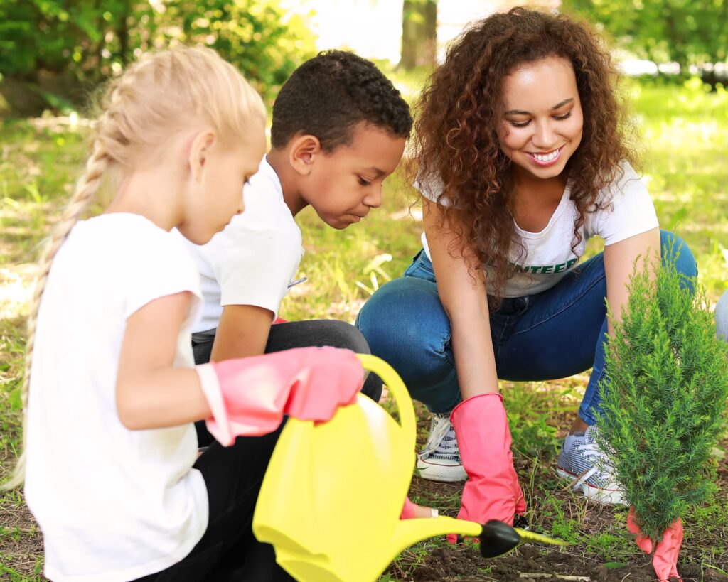 School gardening club - children and teacher planting a tree.