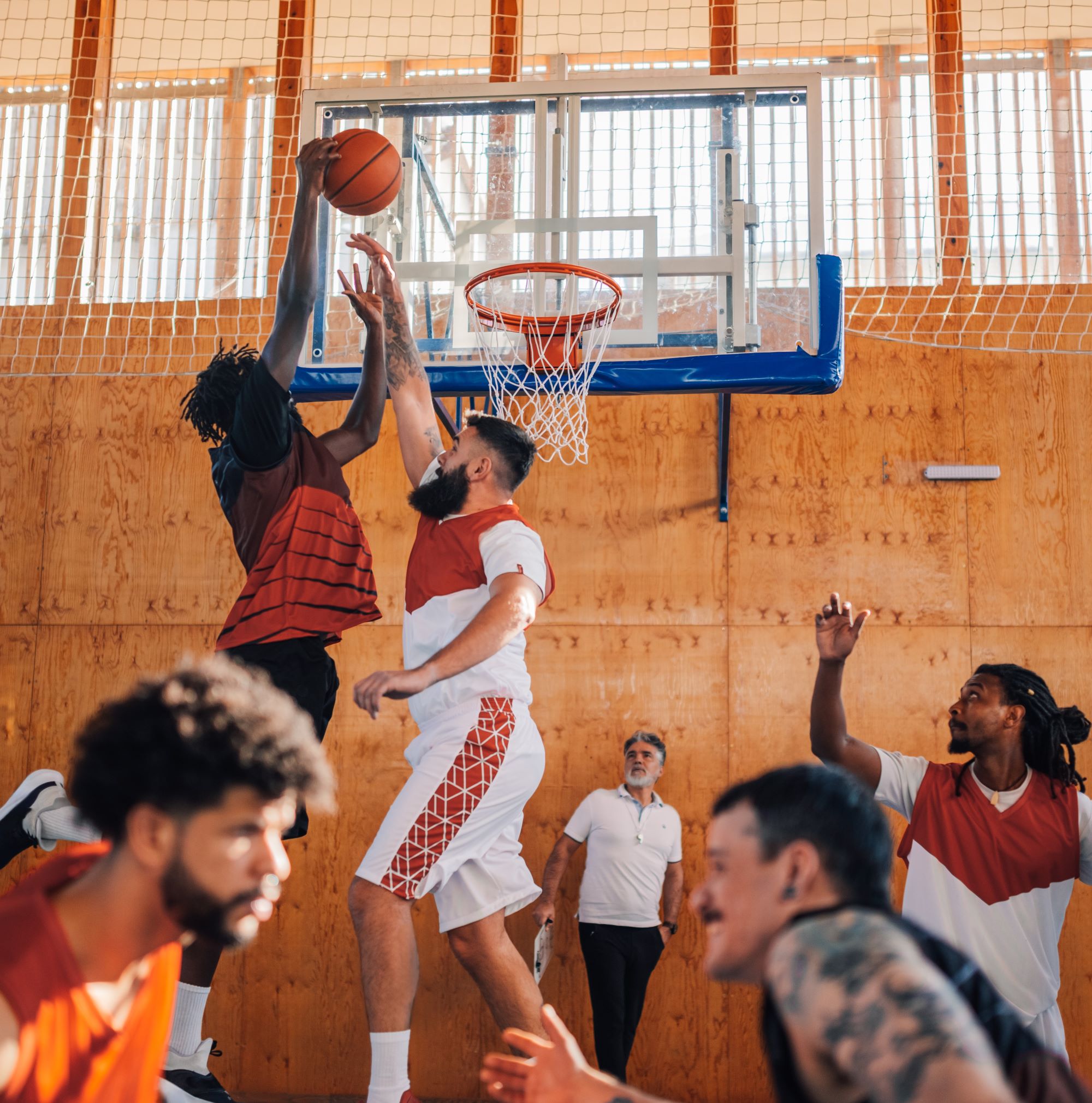 Men playing basketball in a school gym
