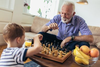 Young boy is playing chess with his grandfather at home.