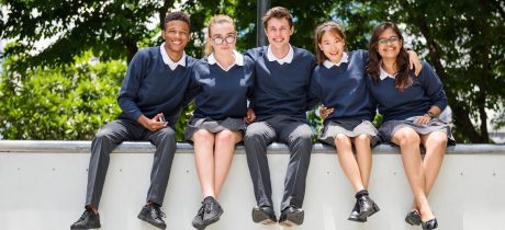 Secondary school pupils sitting on a wall