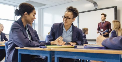 Two female teens are working together during their lesson in a classroom.